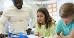 En lärare hjälper två elever.